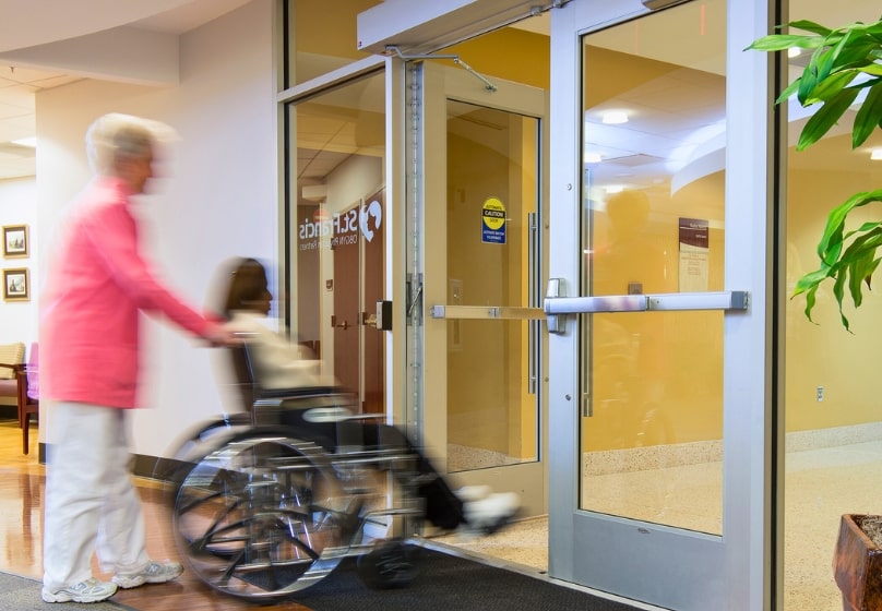 woman in wheelchair passing through a touchless door